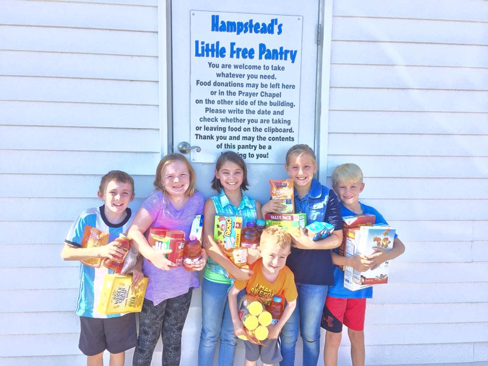 children posing in front of the sign for Hampstead’s Little Free Pantry